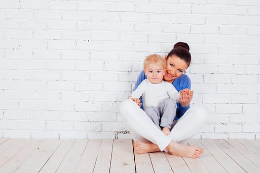 mom and young boy sitting on the floor near the brick wall