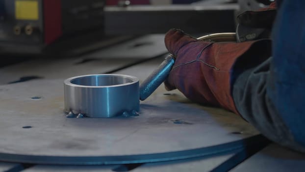 Welder in gloves holds welding with flying sparks. Creative. Sparks while working with welding and steel structures. Welding tube with sparks from metal structure.