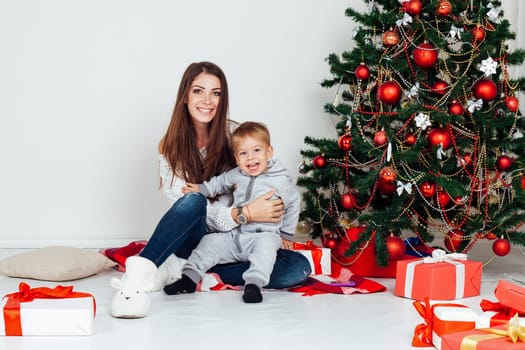 mother and little boy at Christmas tree with gifts