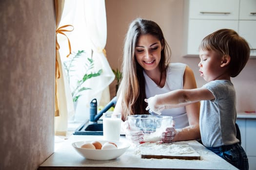 mother and son prepare pie sprinkled with flour