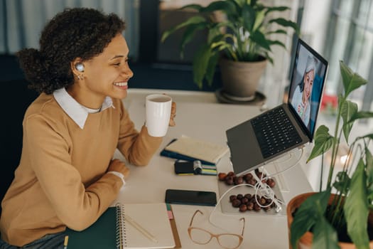 Positive business woman have video conference with client and making notes sitting in office