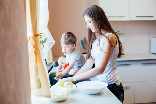 kitchen little son helps mom wash fruits and vegetables in the sink
