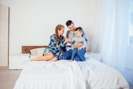 mom dad and son in the morning lying on the bed at home 1