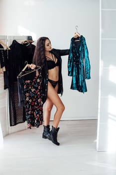 Beautiful woman in lingerie takes different clothes in the wardrobe