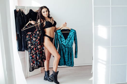 Beautiful woman in lingerie takes different clothes in the wardrobe