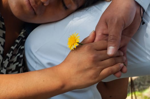 close up of two hands joined with a flower in the middle of the background the face of a latin girl with closed eyes in love and dreamy. valentine's day. High quality photo