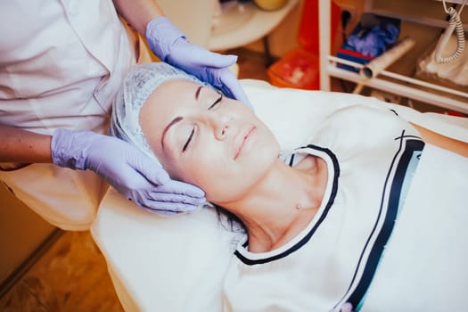 the doctor makes a woman patient procedures esthetician on face