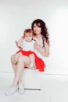 mother and little daughter in red skirts on a white background