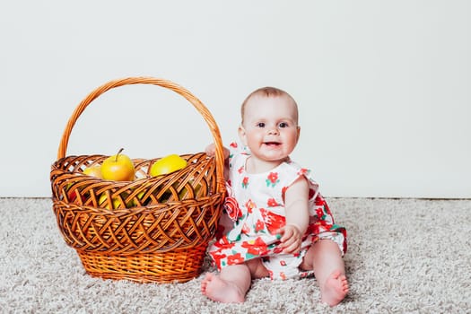 baby girl in a dress with a basket of Green apples