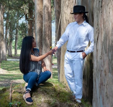 native man from ecuador gives a yellow flower to his indian lover on valentine's day surrounded by many trees. . High quality photo