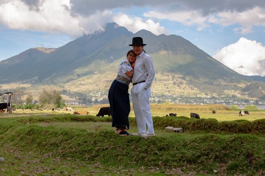 general shot of an indigenous couple from otvalo, ecuador embracing and loving each other in their village surrounded by cattle and the imbabura volcano in the background. valentine's day. High quality photo