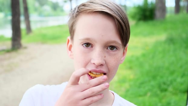 Close-up of chewing handsome boy in nature. Concept. Handsome guy is chewing snack in park. Attractive guy eats snack in nature on summer day.
