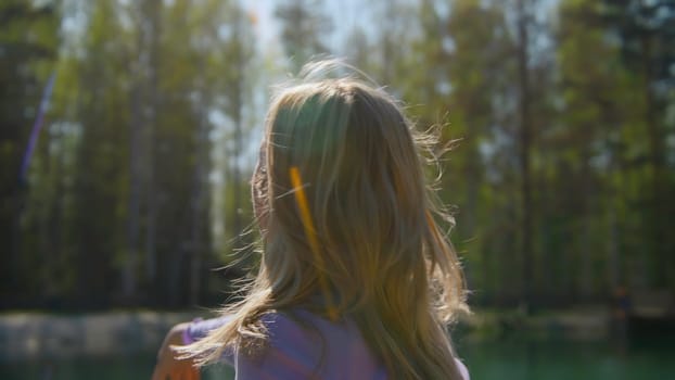 Young woman throwing something. Stock footage. Rear view of young woman throwing stone into lake in summer. Beautiful young woman throws something into lake on sunny summer day.