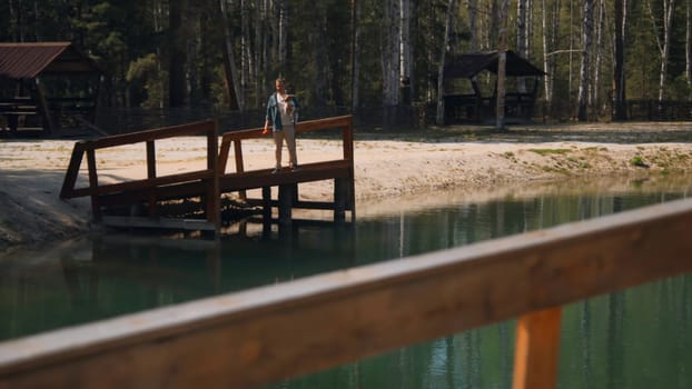 Man with dog on lake pier. Stock footage. Beautiful lake with pier and man holding dog in hands. Relaxing with dog on summer lake in forest on sunny day.