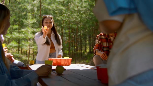 Beer pong with friends. Stock footage. Beautiful young woman playing beer pong with friends. Beer pong game in nature on summer day.