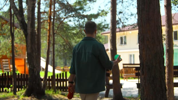 Man with dog and ball walks in park. Stock footage. Man throws dog ball while walking in park on summer day. Man walks with dog and ball on sunny summer day.