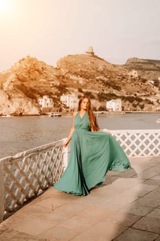 Woman sea trevel green dress. Side view a happy woman with long hair in a long mint dress posing on a beach with calm sea bokeh lights on sunny day. Girl on the nature on blue sky background