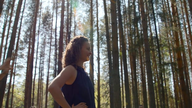 Beautiful young woman stands ready in forest. Stock footage. Young woman smiles beautifully and strikes pose on background of forest. Beautiful woman smiles happily on background of sunny summer forest.