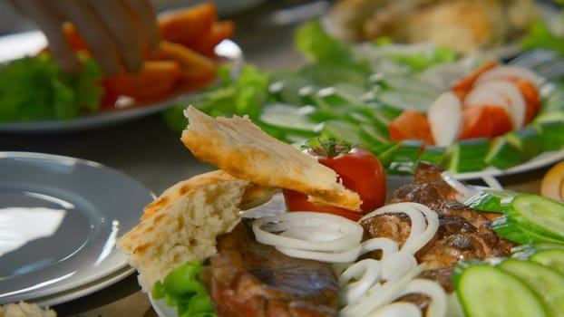 Close-up of table with meat and vegetables in nature. Stock footage. Fresh vegetables and juicy meat on table on sunny summer day. Table with vegetables and meat in nature in summer.
