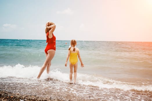 Happy loving family mother and daughter having fun together on the beach. Mum playing with her kid in holiday vacation next to the ocean - Family lifestyle and love concept.