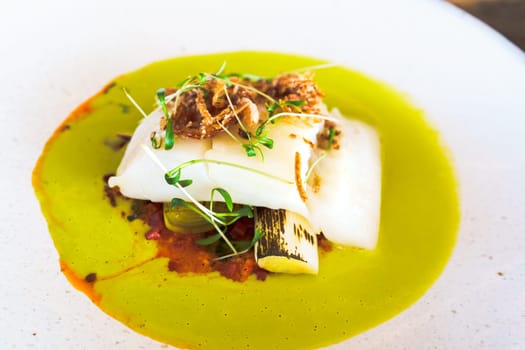 A delectable fillet of fish, expertly cooked and served on a clean, white plate in an upscale restaurant setting, showcasing the epitome of fine dining cuisine.