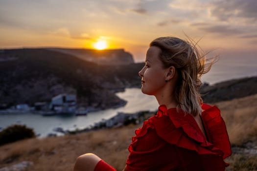 Woman sunset sea mountains. Happy woman siting with her back on the sunset in nature in summer posing with mountains on sunset, silhouette. Woman in the mountains red dress, eco friendly, summer landscape active rest.