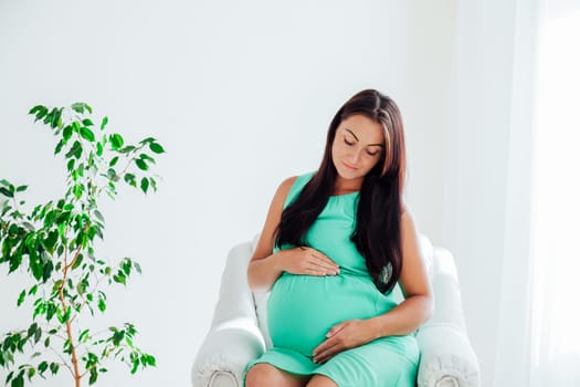 a pregnant woman before childbirth sits in white couch 1