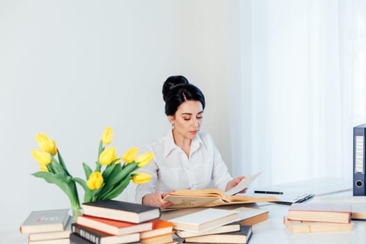 Portrait of brunette in a business suit in the Office behind a table with books