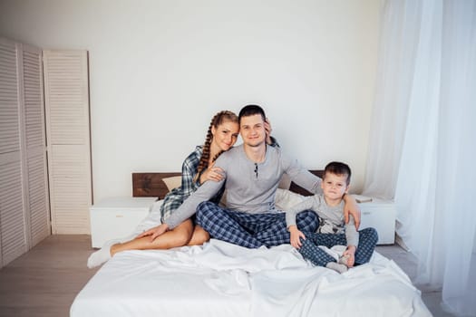 mom dad and son in the morning lying on the bed at home 1