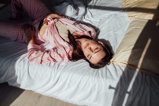 brunette woman in pink Pajamas lying on bed 1