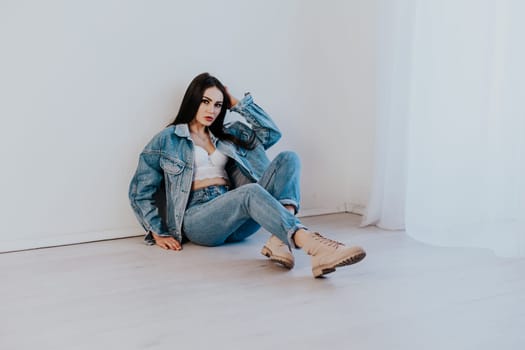 beautiful girl in jeans clothes sitting on the floor in a white room 1