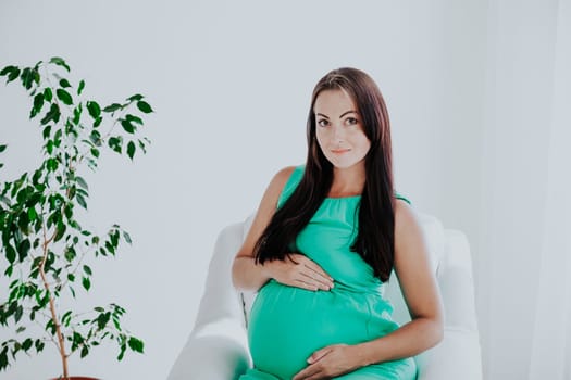 a pregnant woman before childbirth sits in white couch 1