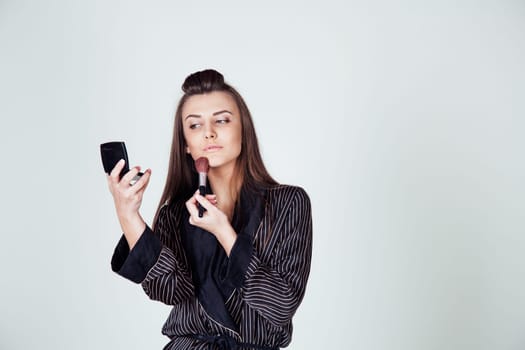 girl in coat makes brush makeup looks in the mirror 1