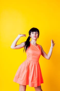 girl in orange dress on a yellow background, and raised his hands up