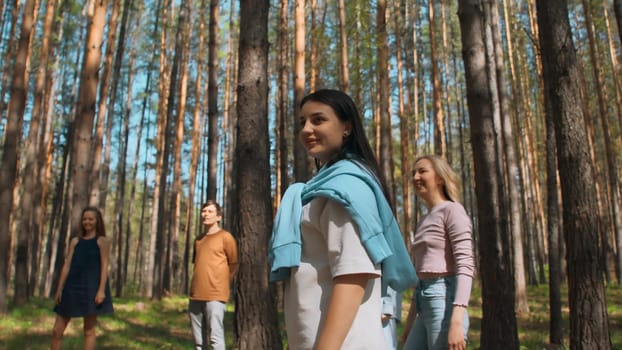 Friends play volleyball in woods. Stock footage. Group of people play ball standing in circle in forest on summer day. Friends relax in nature in sunny weather.