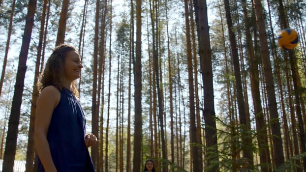 Young woman bounces volleyball ball. Stock footage. Beautiful young woman is having fun playing volleyball in nature in summer. Woman cheerfully hit ball on volleyball in park.