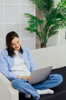 Woman working on laptop sitting on sofa