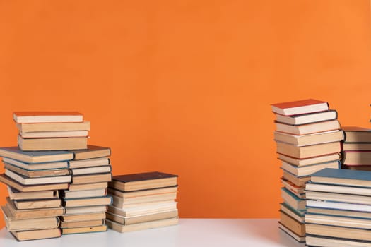 Stacks of books in school library on orange background