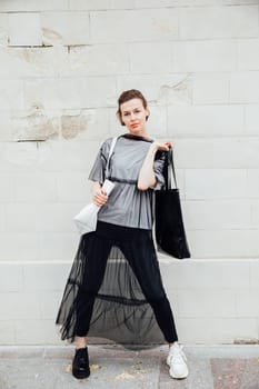 woman in black clothes posing near a white building