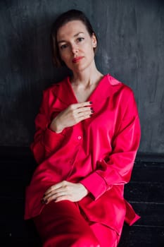 Fashionable woman in crimson pajamas in black room