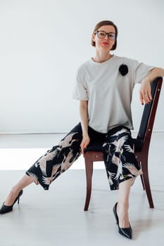 Portrait of a beautiful woman in a summer suit sitting on a chair