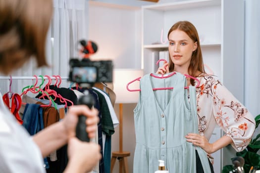 Woman influencer shoot live streaming vlog video review clothes utmost social media or blog. Happy young girl with apparel studio lighting for marketing recording session broadcasting online.