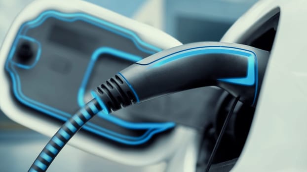 Closeup EV charger plugged into electric car for electric recharging from electric charging station with glowing light cable. Cutting-Edge innovation and future green energy sustainability. Peruse