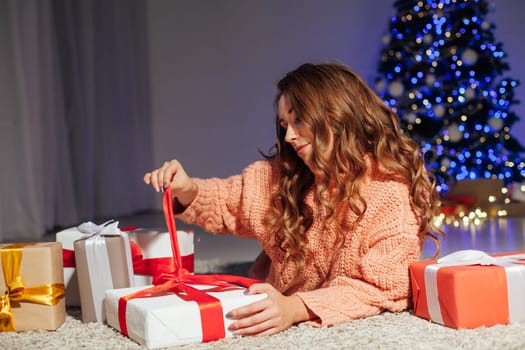 Beautiful woman cuts Christmas gifts at the Christmas tree for the new year lights garland