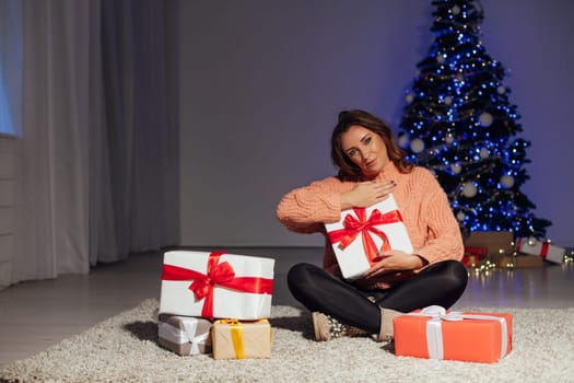 Beautiful woman cuts Christmas gifts at the Christmas tree for the new year lights garland