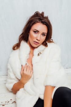 Portrait of a beautiful woman with hair curls in a white fur coat