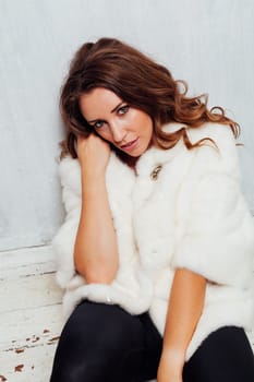 Portrait of a beautiful woman with hair curls in a white fur coat