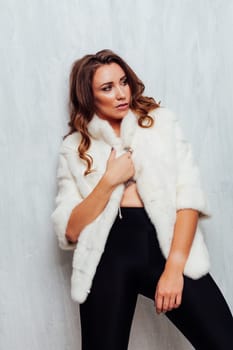 Portrait of a beautiful woman with hair curls in a white fur coat