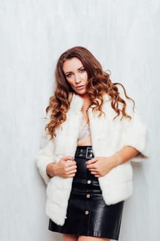 Portrait of a beautiful woman with hair curls in a white fur coat