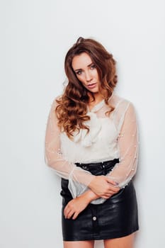 Portrait of a beautiful woman with hair curls in a white blouse and black skirt